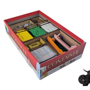 May include: A red board game box titled CONTAINER with a wooden insert organizer. Inside are compartments containing yellow, green, and white square tokens, gold-colored rectangular pieces, a stack of cards, and plastic ship miniatures in orange and pink.
