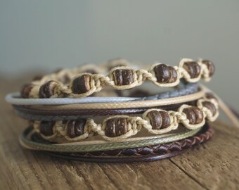 May include: A stack of four bracelets made with brown wooden beads and natural fibers. The bracelets are layered on top of each other, creating a textured and earthy look.