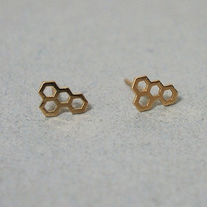 Puede incluir: Un par de pendientes de botón de panal de abeja de color dorado.