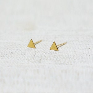 May include: A pair of gold triangle stud earrings. The earrings are small and simple, and they would be a great addition to any jewellery collection.