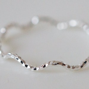 Puede incluir: Un anillo de plata con una banda ondulada y texturizada.