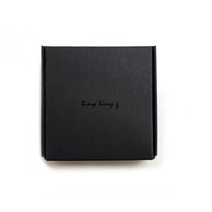 May include: A black square box with the text "tiny tiny &" printed on the top.