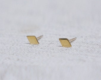 May include: A pair of gold diamond-shaped stud earrings.