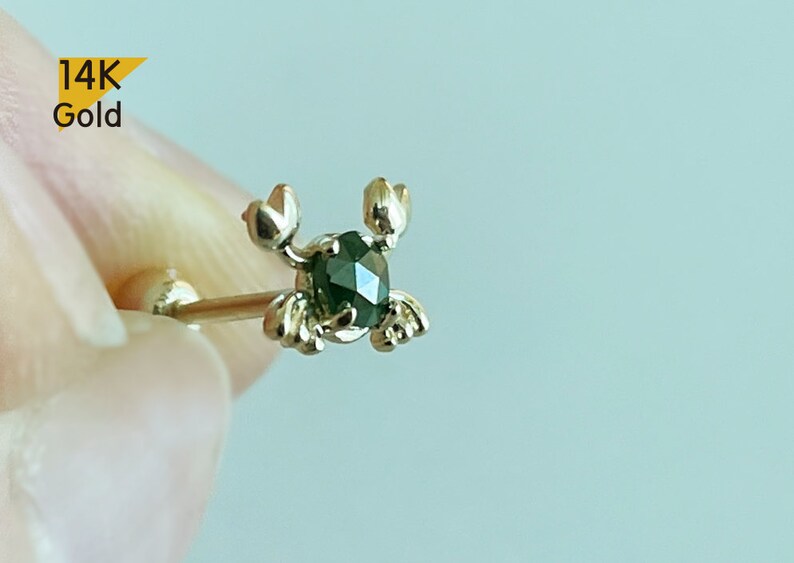 May include: 14K gold crab body jewellery with a green gemstone.