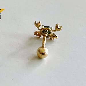 May include: 14K gold crab earring with green and black gemstones. The earring is a stud with a ball post.