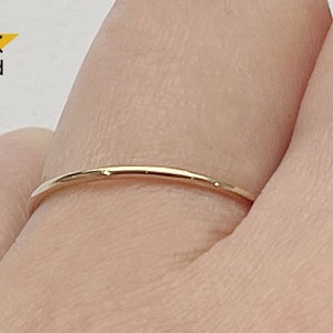 May include: A simple, thin gold band ring on a finger. The ring is 14K gold.