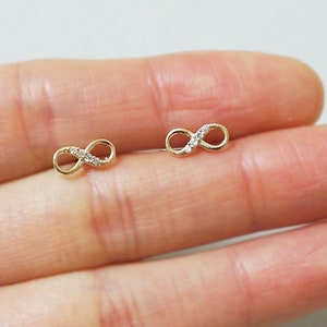 May include: A pair of gold infinity symbol earrings with small clear cubic zirconia stones.