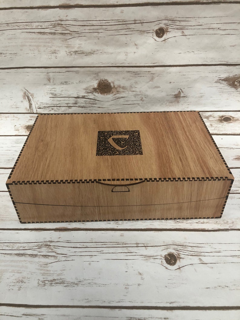 Puede incluir: Una caja de madera con un dise&ntilde;o decorativo e intrincado en la tapa. La caja tiene una peque&ntilde;a manija rectangular en la parte delantera.