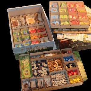 Op de afbeelding: Een houten spelorganizer voor het bordspel "Feast for Odin". De organizer heeft meerdere compartimenten voor het opbergen van de spelonderdelen, waaronder dobbelstenen, meeples en kaarten. De organizer is gemaakt van natuurlijk hout en heeft een lichtbruine afwerking.