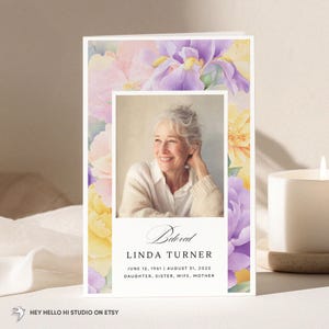 May include: A memorial card with a photograph of a smiling woman, surrounded by a watercolour floral design in purple, pink, and yellow. The card includes the text "Beloved" and the name "LINDA TURNER" with dates and family titles.