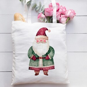 May include: White canvas tote bag with a red and green Santa Claus illustration. The Santa Claus is wearing a red hat, a green coat with white trim, and a white beard.