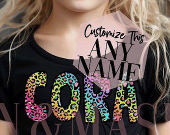 Könnte beinhalten: Ein schwarzes T-Shirt mit einem bunten Leopardenmuster, auf dem vorne "Cora" steht. Der Text ist von einem rosa Kreis mit den Worten "Dieses Design anpassen, beliebiger Name" in schwarzer Schrift umgeben.