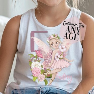 May include: A white sleeveless tank top featuring a graphic of a fairy with pink wings and floral accents, alongside the number five and the name Audrey. A small rectangular tag on the shirt displays the text Customize This ANY AGE.