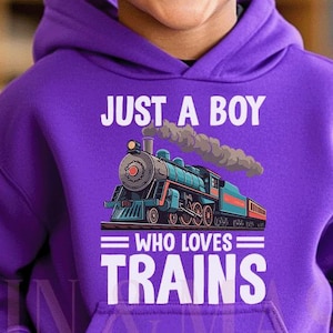 May include: A purple hoodie featuring the text "JUST A BOY WHO LOVES TRAINS" and a graphic of a blue and red train. The hoodie is worn by a smiling child with curly dark hair.