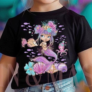 Könnte beinhalten: Schwarzes T-Shirt mit einem Meerjungfrau-Motiv in Lila, Rosa und Türkis. Das Design umfasst Fische und Muscheln. Das T-Shirt wird von einem jungen Kind mit blonden Haaren und blauen Augen getragen.