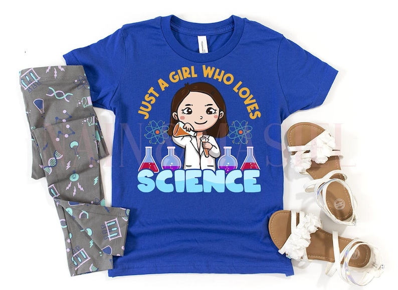 May include: A blue t-shirt with the text "Just a girl who loves science" and a cartoon illustration of a girl wearing a lab coat and holding a beaker. The girl has brown hair and is smiling.