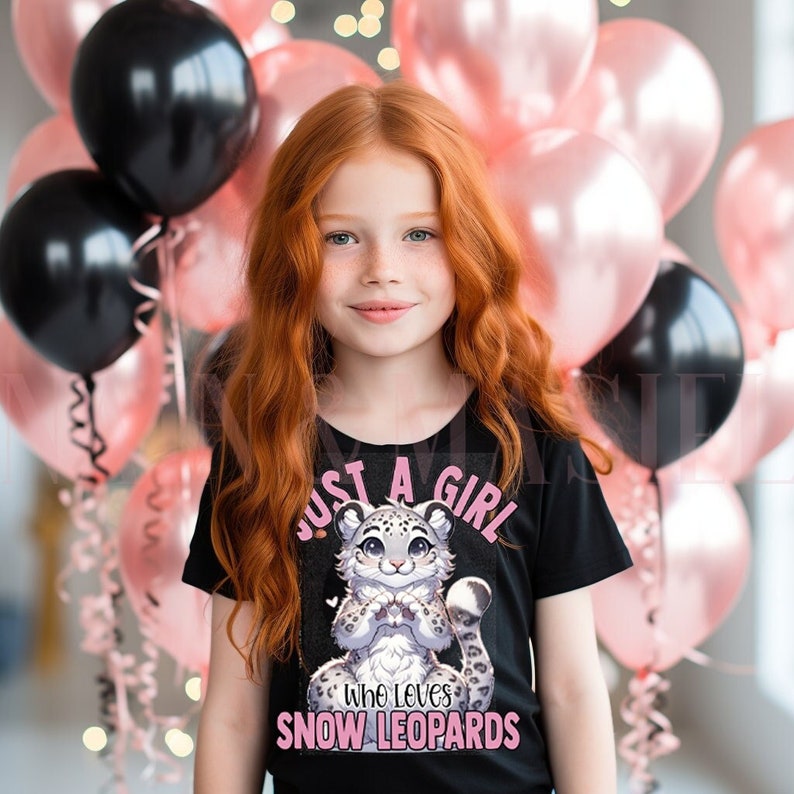 May include: A young girl with red hair is wearing a black t-shirt with a pink and white snow leopard graphic and the text "Just a girl who loves snow leopards".