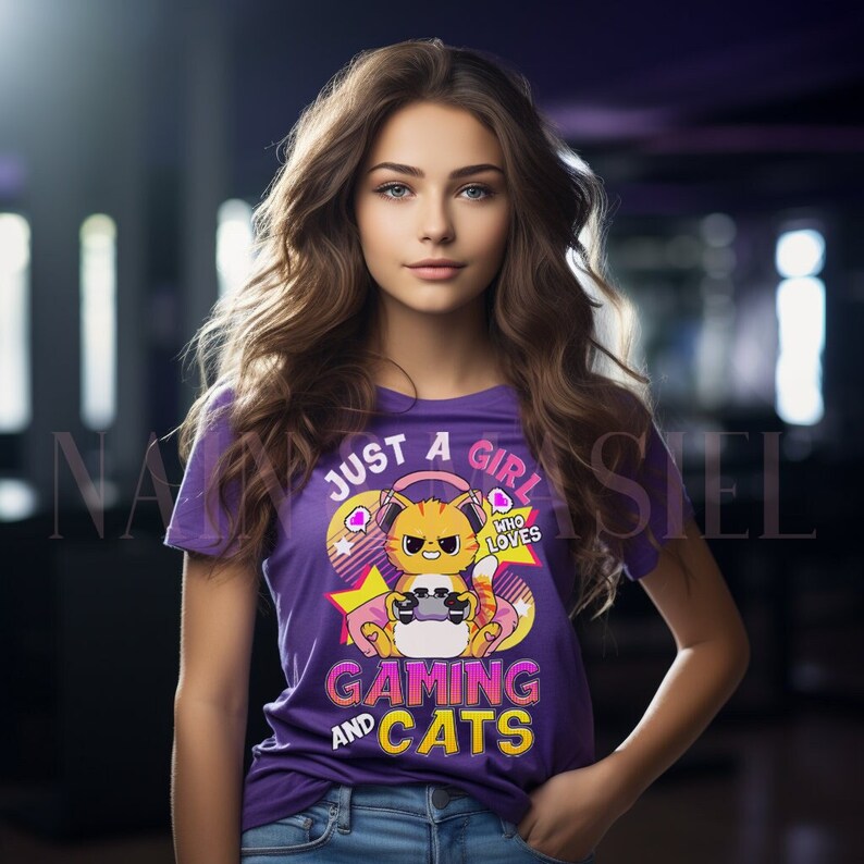 May include: A purple t-shirt with the slogan "JUST A GIRL WHO LOVES GAMING AND CATS". The design includes a cartoon cat with headphones and a game controller. The shirt is worn with blue jeans.