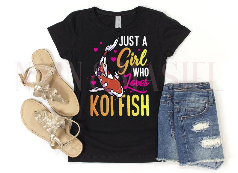 May include: A black short-sleeve t-shirt featuring a graphic of a koi fish with pink hearts and the text "JUST A GIRL WHO LOVES KOI FISH" in yellow and pink, paired with a pair of gold metallic sandals and blue denim shorts with distressed details.