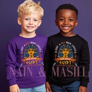 May include: Two children's long-sleeved shirts, one purple and one black, each featuring an Ancient Egypt graphic. The graphic includes the text "Just a boy who loves Ancient Egypt" and the names "Nain & Masiel".