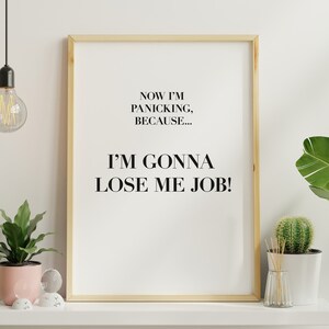 May include: A framed print with the text "Now I'm panicking, because... I'm gonna lose me job!" The print is hanging on a white wall with a light bulb hanging from the ceiling above it. There are two plants in pots on a white shelf below the print.