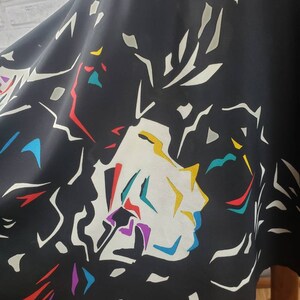 May include: Black skirt with a colorful abstract floral print. The print features white, yellow, red, blue, purple, and teal colors.