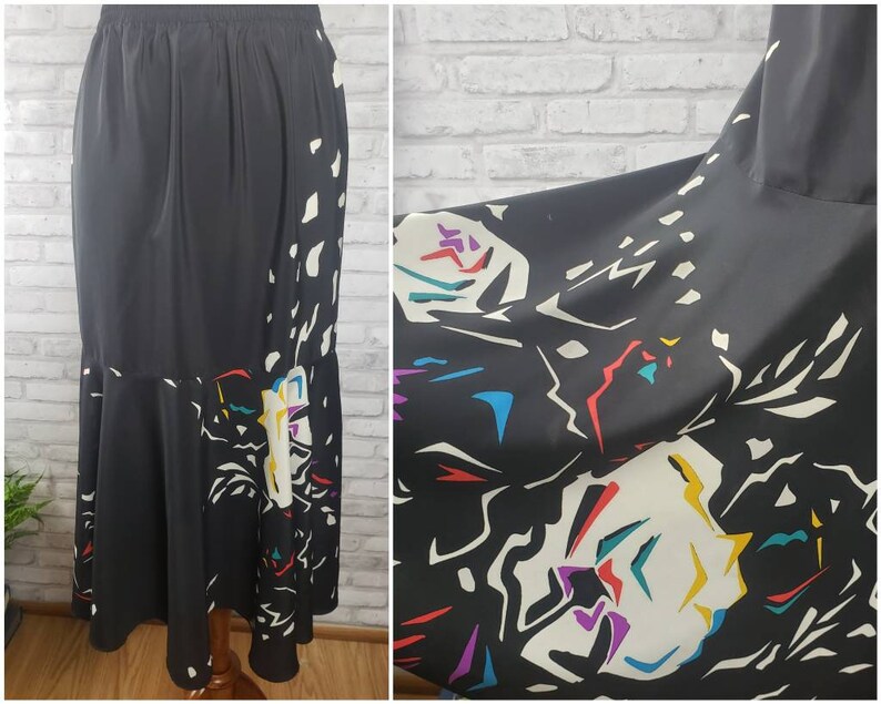 May include: A black maxi skirt with a colorful abstract print. The skirt has a flared hem and a high waist.