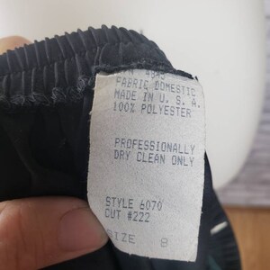 May include: Black pleated skirt with a white tag that reads "FABRIC DOMESTIC MADE IN U.S.A. 100% POLYESTER", "PROFESSIONALLY DRY CLEAN ONLY", "STYLE 6070 CUT #222", and "SIZE 8".