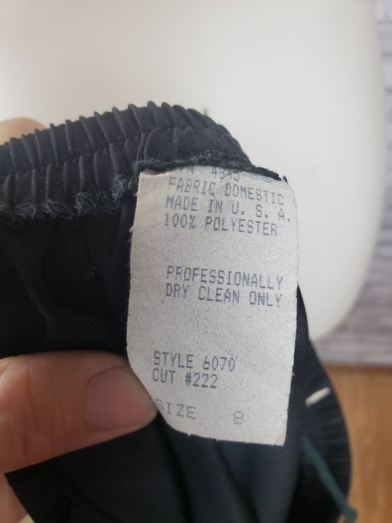 May include: Black pleated skirt with a white tag that reads "FABRIC DOMESTIC MADE IN U.S.A. 100% POLYESTER", "PROFESSIONALLY DRY CLEAN ONLY", "STYLE 6070 CUT #222", and "SIZE 8".