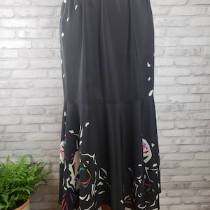 May include: A black midi skirt with a white and colorful abstract print. The skirt has a gathered waistband and a flared hem.