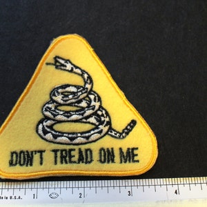 May include: Yellow triangular patch with a coiled rattlesnake and the text "Don't Tread On Me".