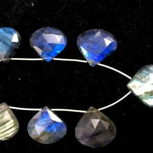 May include: A strand of faceted labradorite gemstone beads in shades of blue, green, and grey. The beads are teardrop shaped and strung on a silver wire.