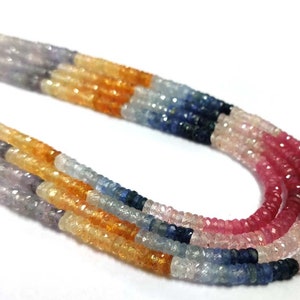 May include: A multi-strand necklace made of faceted gemstone beads in shades of green, lavender, orange, blue, pink, and red. The beads are arranged in a graduated pattern, with the largest beads at the bottom and the smallest beads at the top.