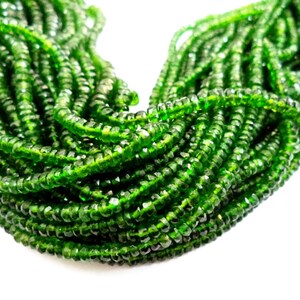 May include: Close-up of a collection of faceted, emerald green beads. The beads are strung together, creating a dense, textured appearance. The color is vibrant and the facets catch the light, giving them a sparkling effect.
