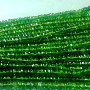 May include: Strands of faceted green gemstone beads. The beads are a vibrant, deep green color and appear to be strung together. The beads are small and evenly sized, creating a textured surface. The image is well-lit, highlighting the beads' sparkle.