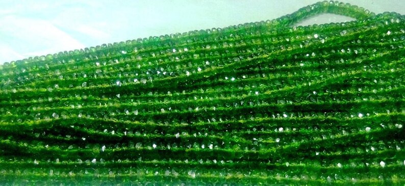 May include: Strands of faceted green gemstone beads. The beads are a vibrant, deep green color and appear to be strung together. The beads are small and evenly sized, creating a textured surface. The image is well-lit, highlighting the beads' sparkle.