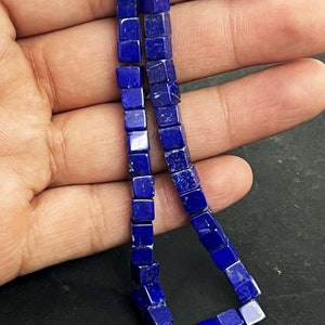 Puede incluir: Una hebra de cuentas de piedra preciosa de lapislázuli azul oscuro, cada cuenta tiene forma de cubo.