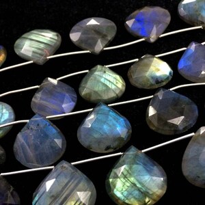 May include: A strand of iridescent labradorite gemstone beads in a teardrop shape. The beads are strung on silver wire and have a blue, green, and gold colour.