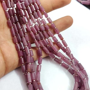 Könnte beinhalten: Eine Strähne aus violetten Edelsteinperlen, jede Perle ist facettiert und rechteckig geformt. Die Perlen sind auf einem Silberdraht aufgefädelt.