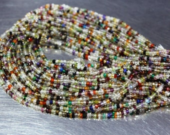 May include: A strand of colorful gemstone beads, including clear, green, red, blue, and purple beads. The beads are small and round, and they are strung together on a clear thread.