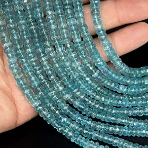 May include: A strand of light blue aquamarine gemstone beads. The beads are faceted and have a slightly irregular shape. The beads are strung on a clear thread and are approximately 4mm in diameter.