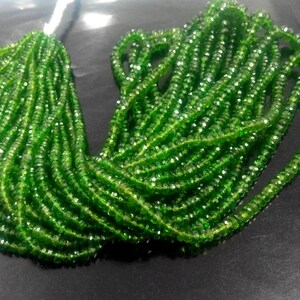 May include: A collection of bright green gemstone beads. The beads are small, faceted, and strung together, creating a shimmering effect. The strands are bundled together, ready for jewelry making.