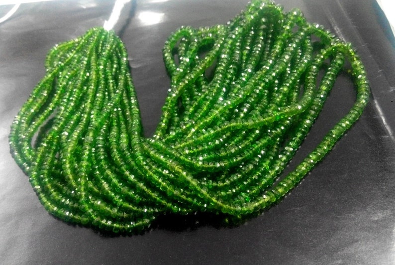 May include: A collection of bright green gemstone beads. The beads are small, faceted, and strung together, creating a shimmering effect. The strands are bundled together, ready for jewelry making.