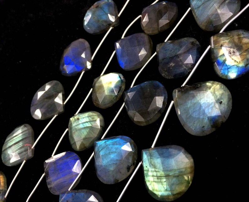 May include: A strand of faceted labradorite gemstone beads in a teardrop shape. The beads are strung on silver wire and have a blue, green, and black iridescent sheen.