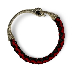May include: A black and red braided bracelet with a silver snake head clasp.