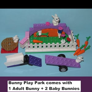 May include: A colorful Bunny Play Park set made of toy blocks. The set includes a purple arch, a white fence, and a seesaw. The set comes with one adult bunny and two baby bunnies. Carrots and flowers are also included.