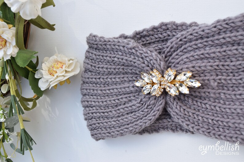 May include: Gray knitted headband with a gold and crystal embellishment. The headband is a simple, elegant design that can be worn with any outfit.