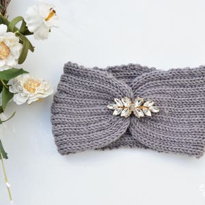 May include: A gray knitted headband with a decorative crystal embellishment. The headband is made of a soft, comfortable fabric and is perfect for keeping your ears warm in the winter.