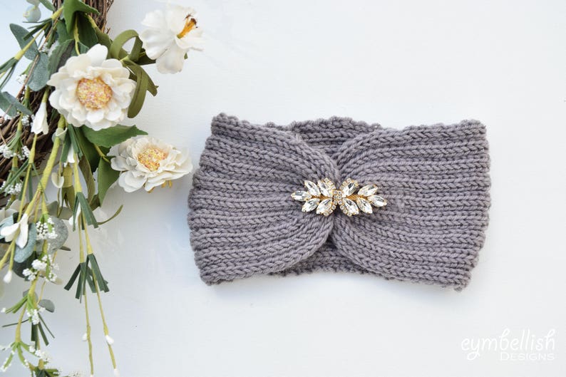 May include: A gray knitted headband with a decorative crystal embellishment. The headband is made of a soft, comfortable fabric and is perfect for keeping your ears warm in the winter.