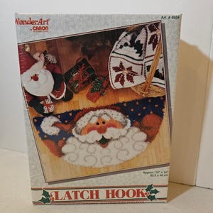 May include: A WonderArt by Caron International latch hook kit box featuring a finished Santa Claus rug design. The box displays the text Art. # 4659, LATCH HOOK, and dimensions of 33 inches by 16 inches. The packaging shows a completed rug project.